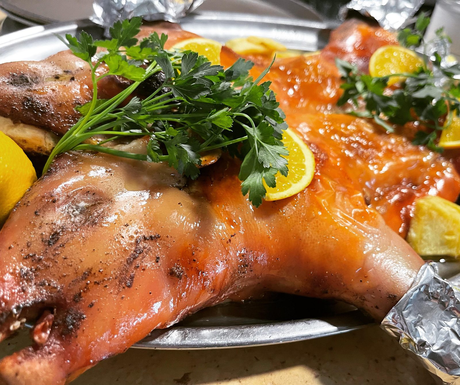 Cochinillo asado a la segoviana con piel crujiente, servido en bandeja con lim&oacute;n y perejil